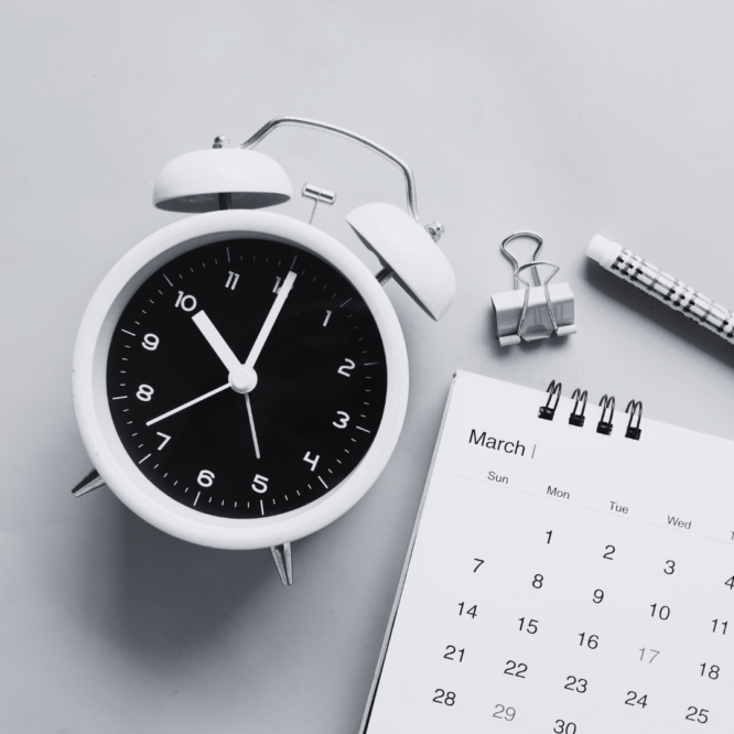 a black and white photo with a clock and calendar and pen