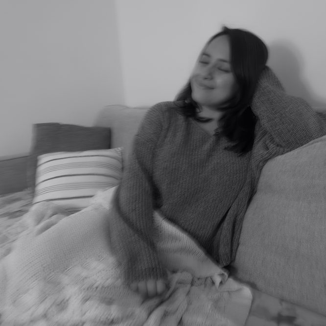 A black-and-white photo of me smiling peacefully with my eyes closed while sitting on my couch.